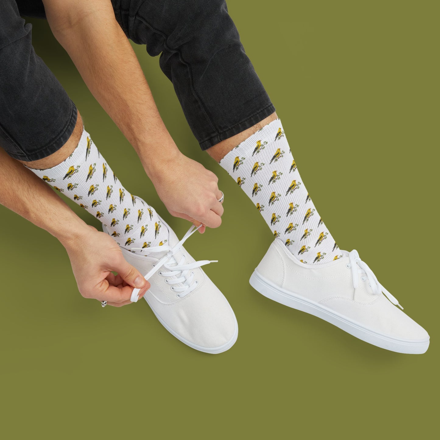 Person wearing white socks with bird pattern and white sneakers on a green background